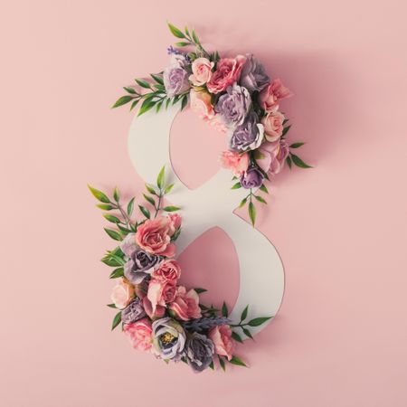 Colorful spring flowers of pink, and purple around the number “8” on pink background