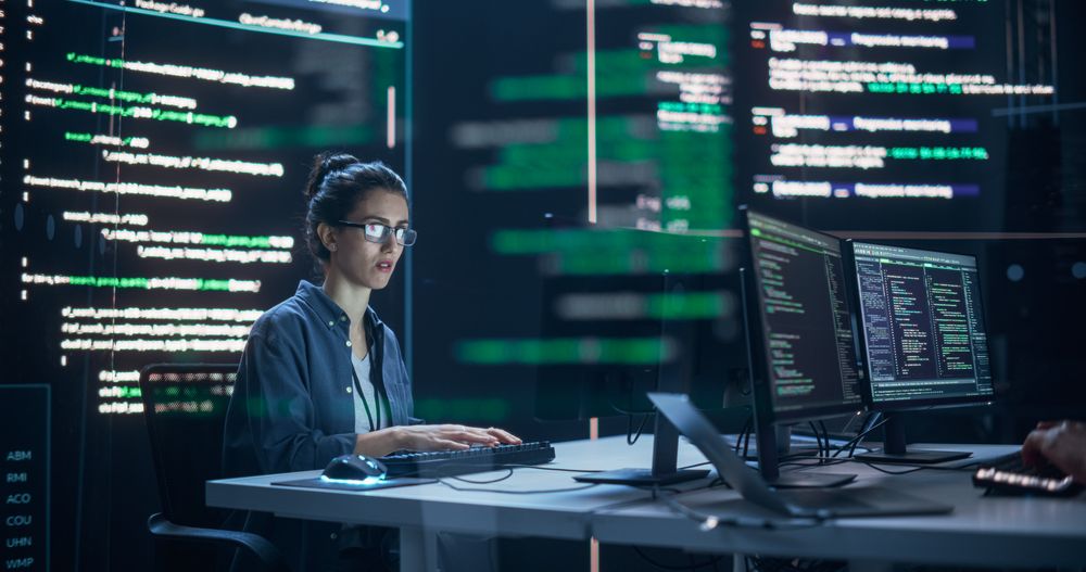 Focused Woman Working as a Developer, Surrounded by Big Screens Displaying Lines of Code in a Monitoring Room.