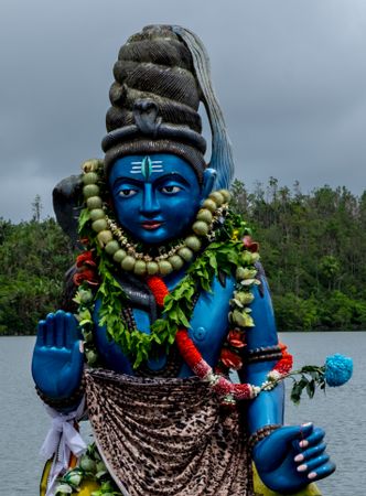 Blue Shiva statue on cloudy day by the lake