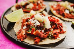 Pepper and lime near tacos al pastor and sauces