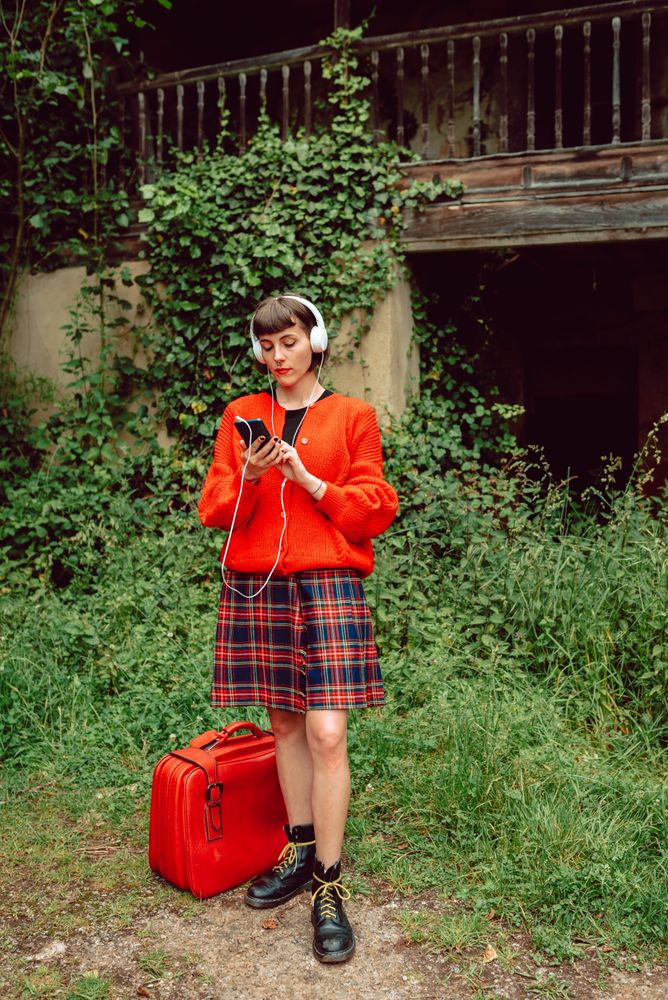 Woman in headphones with suitcase choosing music