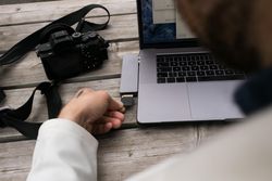 Tattooed hands inserting memory card into laptop