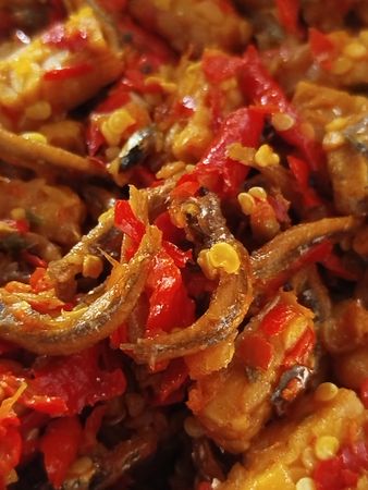 Close-up of a spicy Indonesian dish made with crispy anchovies, chopped red chilies, and tempeh, stir-fried together for a bold, savory, and fiery flavor explosion.