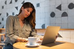Woman surfing internet on laptop at cafe table