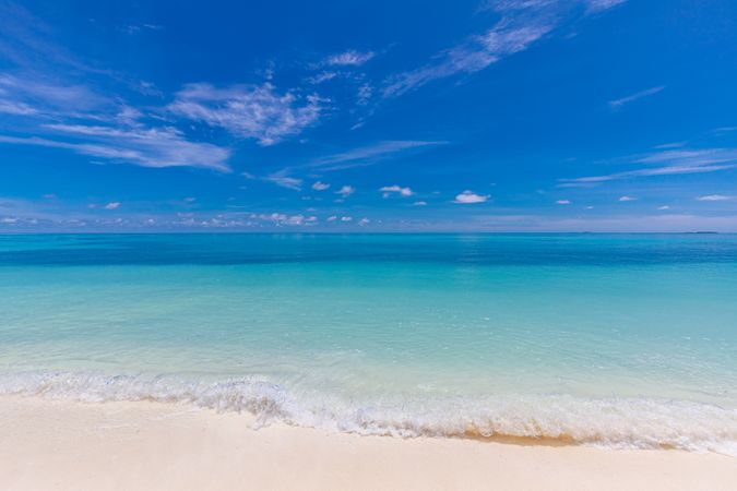 Blue waves coming in on a beach in the Maldives