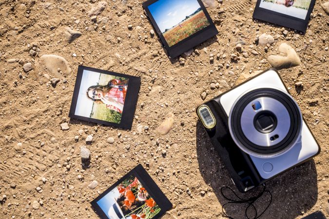 Stylish accessories and instant photos on sandy ground