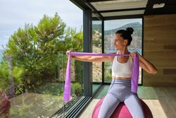 Energetic sportswoman doing exercises with resistance band in fitness studio