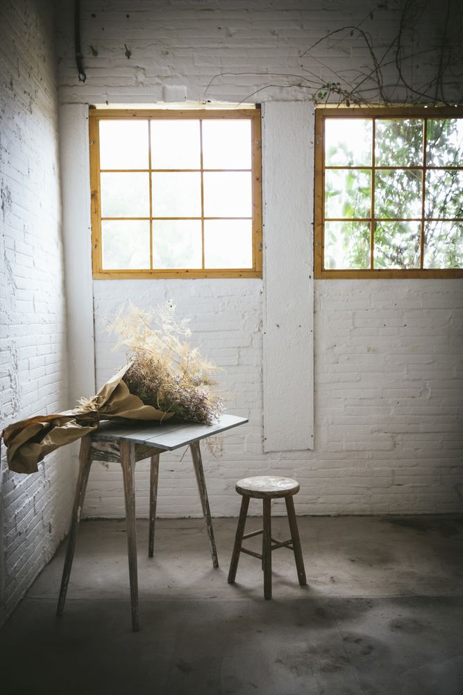 Bunch of plant in paper on table near stool in grey room