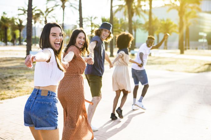 Multiethnic group of young friends running happily together while holding hands