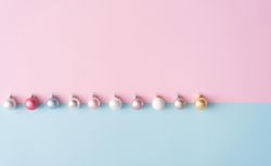 Row of colorful Christmas baubles on blue and pink pastel background