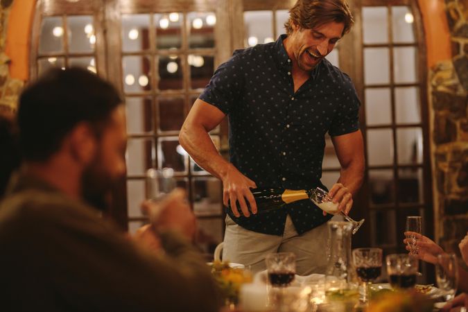 Man serving champagne to friends at dinner party