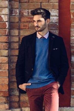 Handsome man leaning on brick wall outside wearing elegant suit