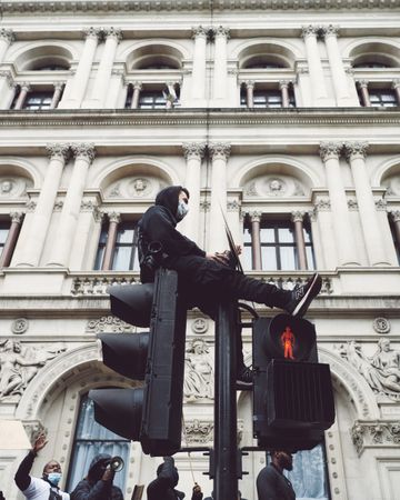 London, England, United Kingdom - June 6th, 2020: Man in mask sitting atop traffic lights