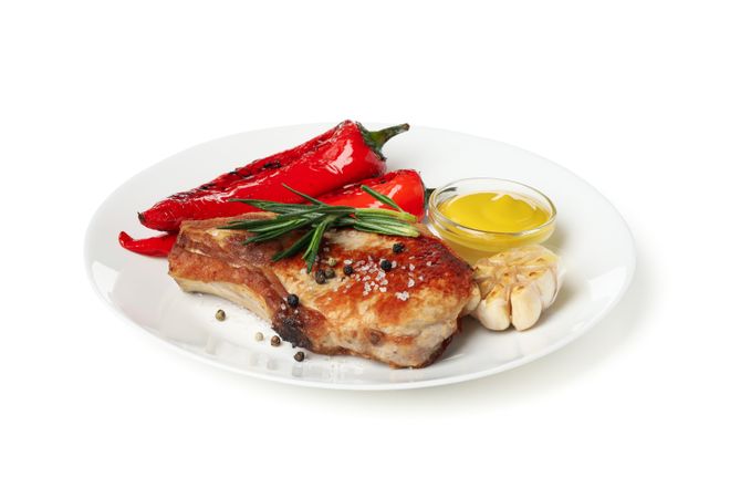 Plate with fried steaks and vegetables isolated on light background