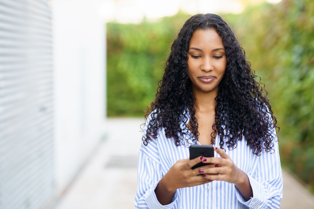A young woman interacts with her smartphone candidly in a lively urban outdoor setting