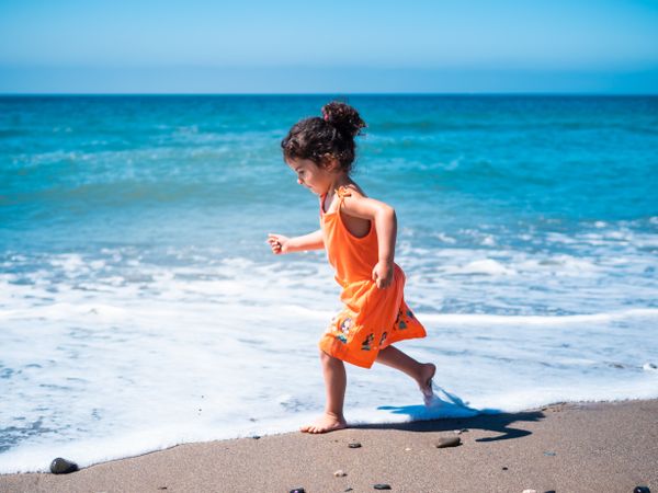 Little girl playing on beach and running
