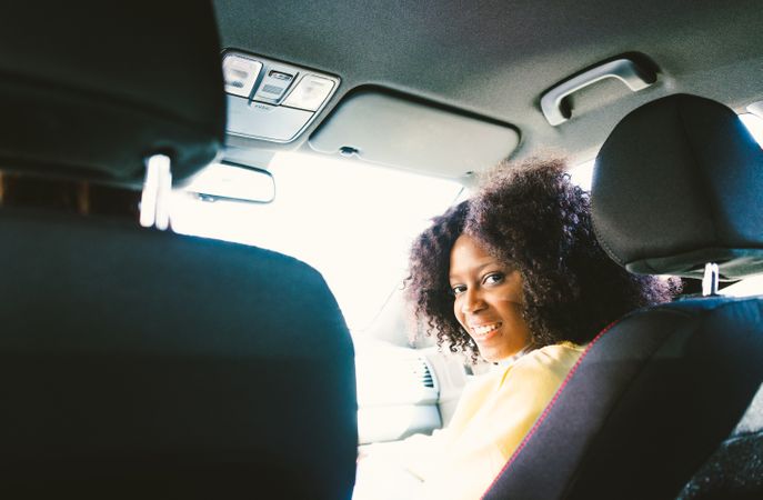 Woman with afro hair peeking out of the car .