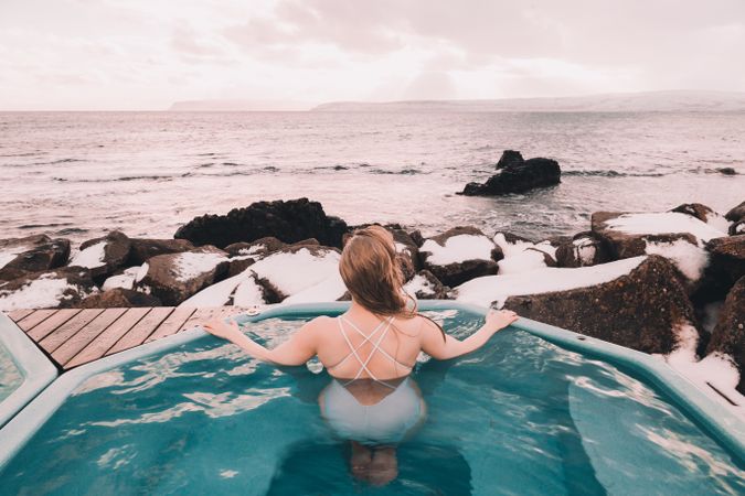 Woman sitting in pool near stones