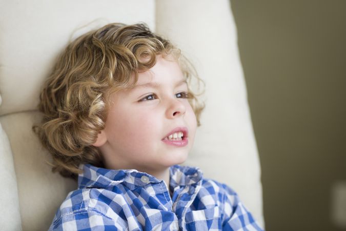 Cute Blonde Boy Daydreaming and Sitting in Chair