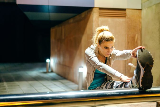 Woman stretching her legs before training at night in town