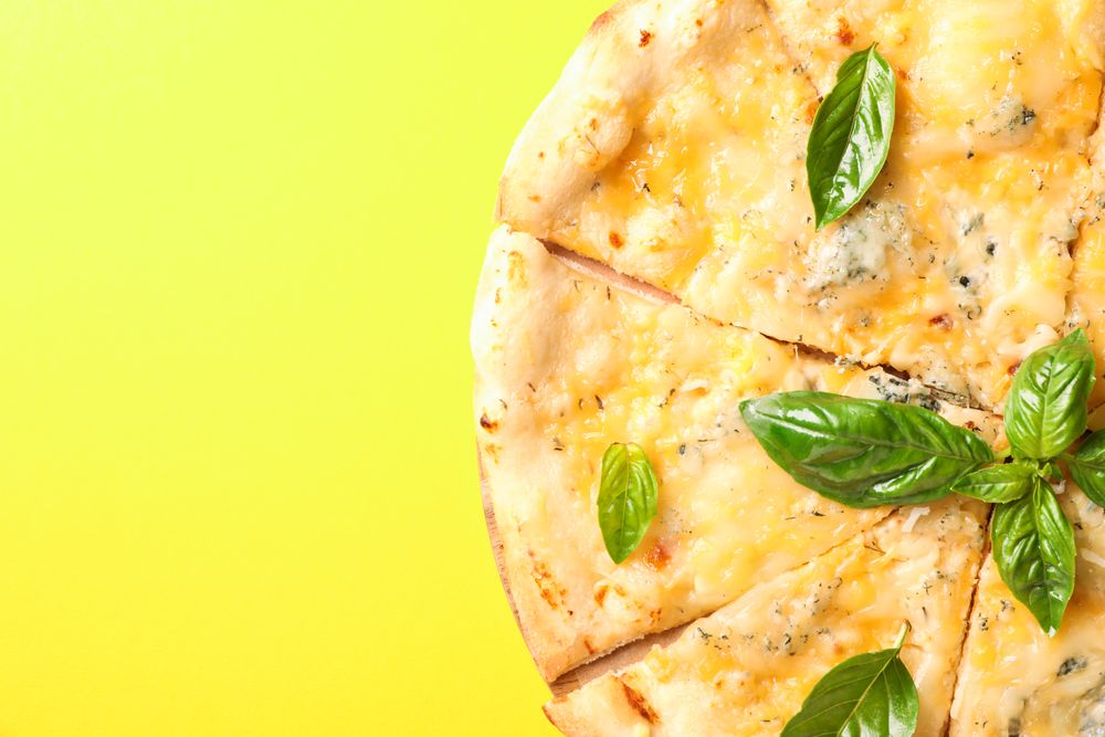 Cheese pizza on yellow background, copy space