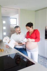 Couple looking through two recipe books in kitchen