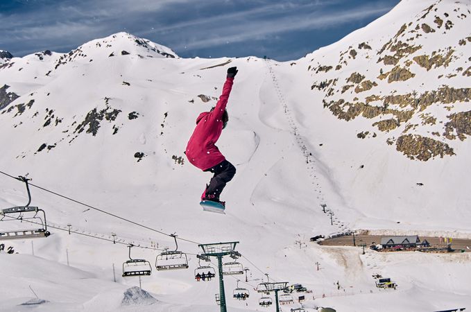 Unrecognizable snowboarder jumping on slope