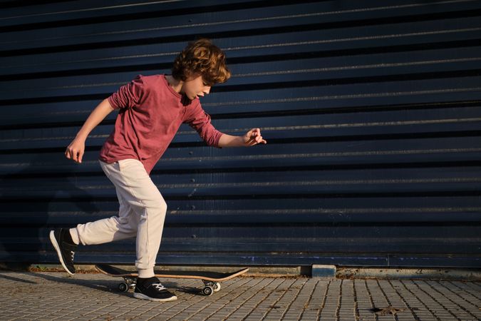 Little skater running near skateboard