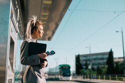 Thoughtful woman with ponytail hair holding tablet and waiting train