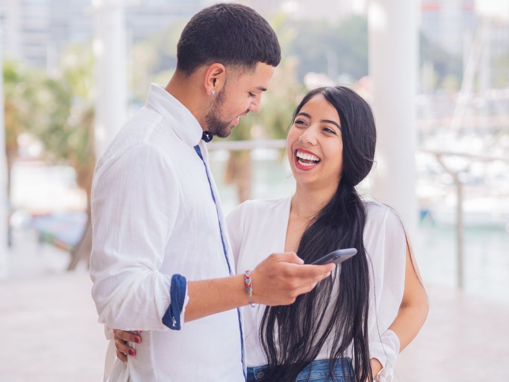 Man messaging on smartphone standing with woman