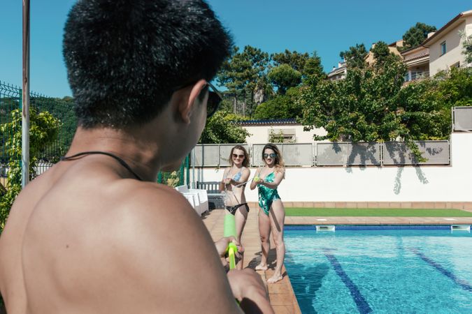 Friends playing with water pistols in the pool