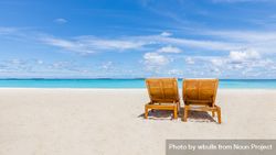 Two lounge chairs on an empty tropical beach 4BDjW0