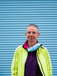 Older woman in neon wind breaker in front of blue wall