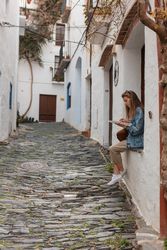 Full length side view of young woman sitting on window ledge with a paper map