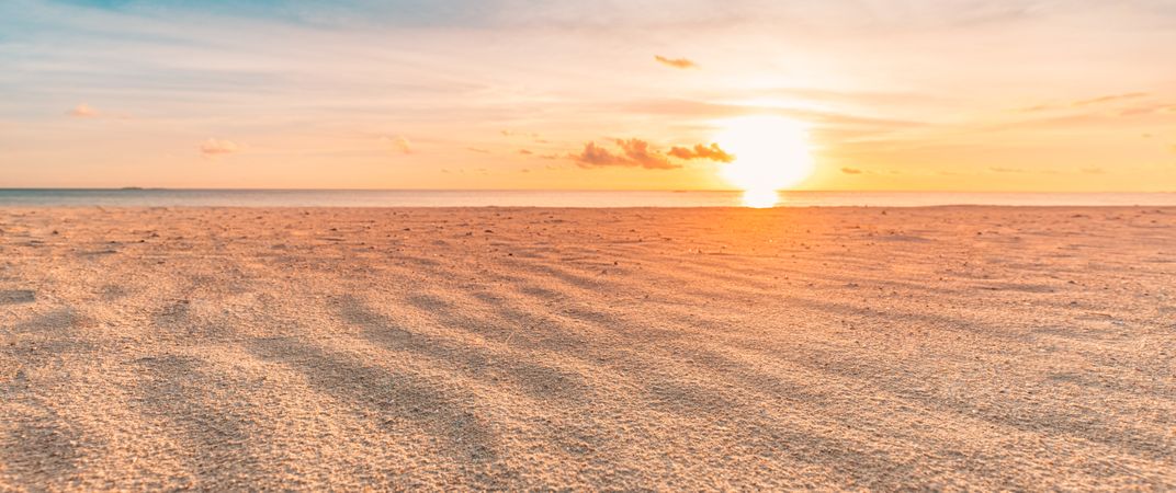 Sand on the beach as the sun sets over the ocean, wide