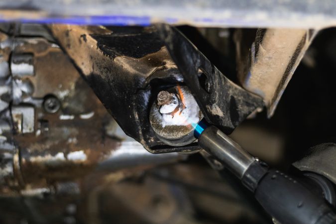 Anonymous repairman removing car details with torch during work in auto service