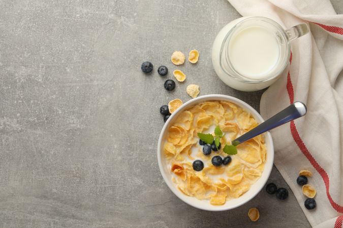 Concept of breakfast with muesli, milk and blueberry on gray table