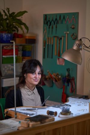 Female jeweler working in workshop with different tools and sket