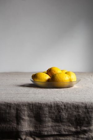 Ripe juicy lemons in plate on table