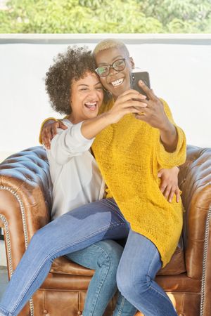 Diverse lesbian women hugging and taking selfie