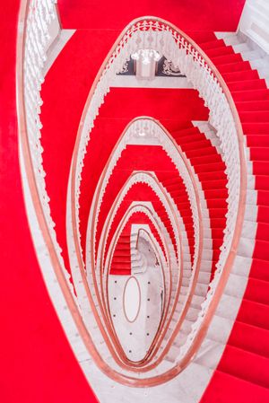 Spiral marble stairs with red carpet