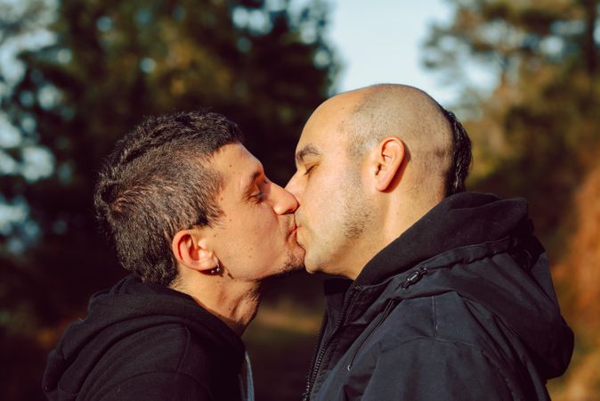 Men hugging and kissing in park