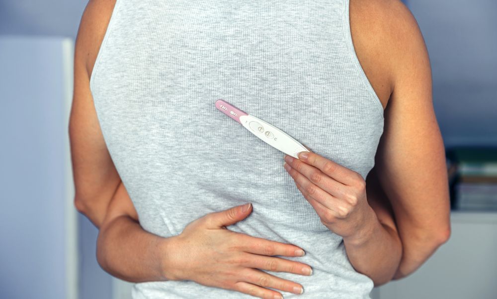 Couple hugging while woman's hands holds a pregnancy test