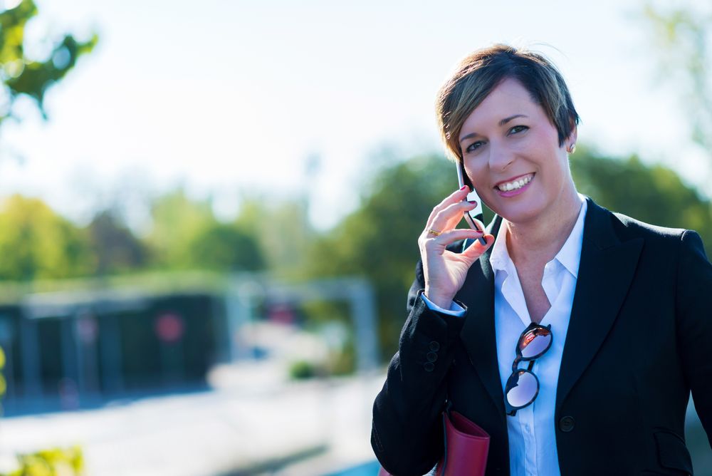 Happy woman standing in park speaking on phone