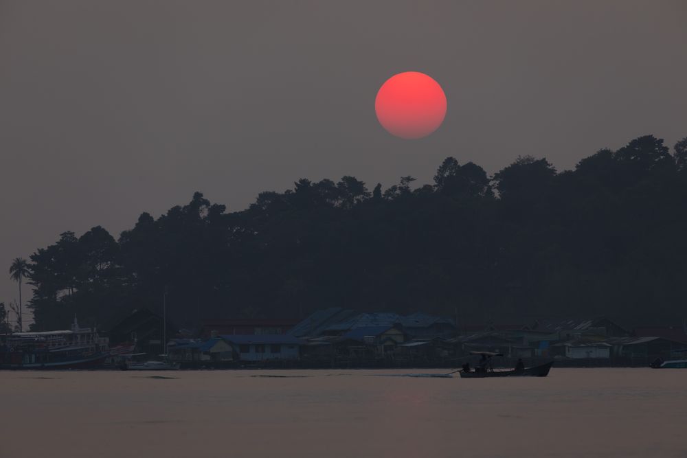 Red bright sun behind rainforest that surrounds small town of Bang Bao, on the island of Koh Chang