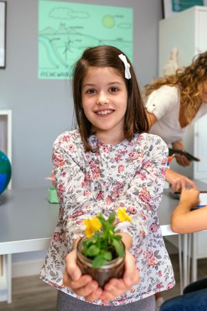 Female student showing to camera a pansy plant in ecology classroom