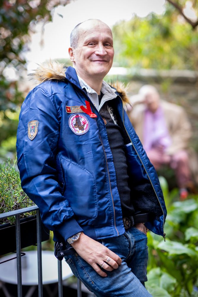 Older man leaning on rail in blue jacket