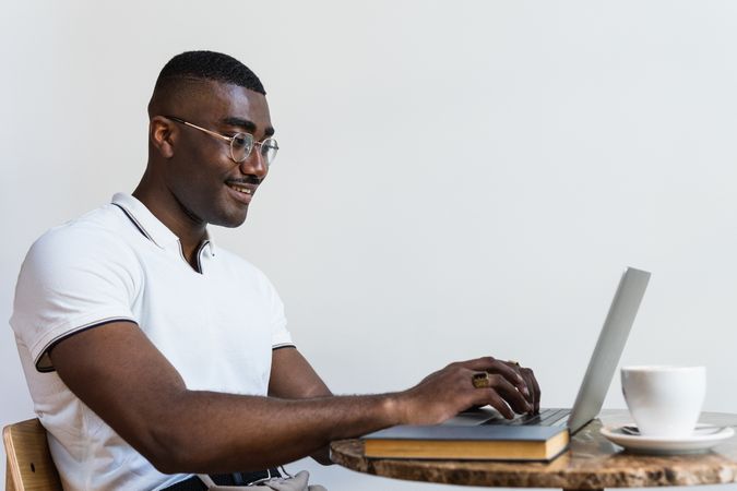 Black man using laptop at table in cafe
