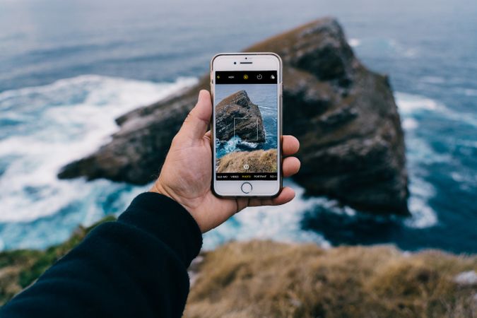 Person taking photo of cliffs and sea