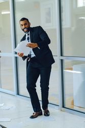 Happy businessman in suit and tie throwing papers in the air in office